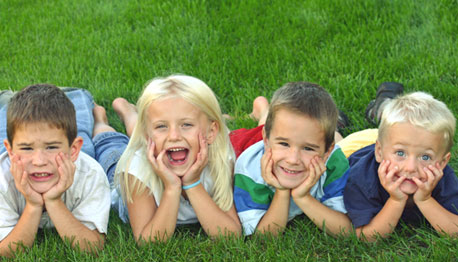 children lined up outside on grass smiling